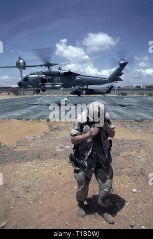 Il 29 ottobre 1993 A U.S. Soldato dell'esercito gira le spalle per la tempesta di sabbia come un US Navy Sikorsky SH-60 Seahawk elicottero dall'USS Abraham Lincoln decolla dall'heli-pad a UNOSOM HQ a Mogadiscio, in Somalia. In background, un esercito americano UH-60 Black Hawk elicottero è solo lo sbarco. Foto Stock