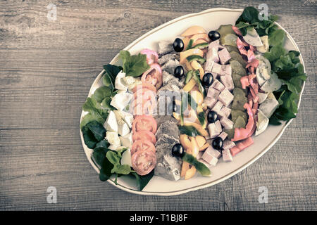 Un famoso piatto della cucina americana - insalata Cobb, costituito da verdi, uova, pomodori, formaggi, prodotti a base di carne, impilati in fila su di un ampio piatto e poure Foto Stock