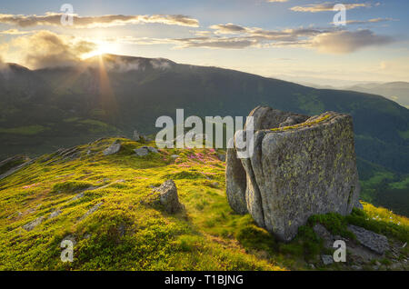 Paesaggio di estate in montagna con il sole nascosto dietro la cresta Foto Stock