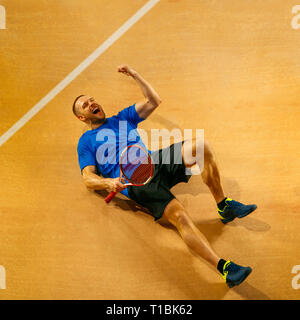 Ritratto di un bel tennista celebra il suo successo su una corte dello sfondo. Le emozioni umane, vincitore, sport, concetto di vittoria Foto Stock