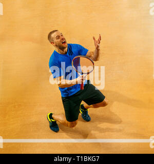 Ritratto di un bel tennista celebra il suo successo su una corte dello sfondo. Le emozioni umane, vincitore, sport, concetto di vittoria Foto Stock