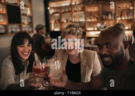 Sorridente amici tifo insieme con bevande a un tavolo bar Foto Stock