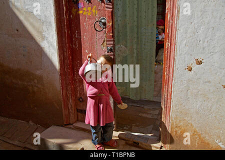 Piccolo Uighur bambino bere acqua fuori della sua casa, Kashgar Città Vecchia, Xinjiang Regione Autonoma, Cina. Foto Stock