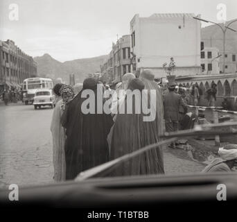 Anni sessanta, Afghanistan, una foto dalla parte anteriore del pullman che mostra un gruppo di donne arabe nel copricapo e lunghe vesti a piedi giù per una strada polverosa nella città capitale di Kabal. Foto Stock