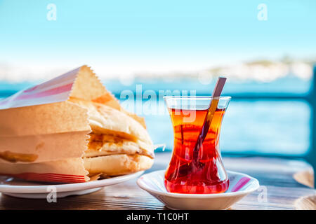 Tradizionale panino turco - 'Balik ekmek' e tè in un tulipano a forma di tazza di trazione. Messa a fuoco selettiva. Foto Stock