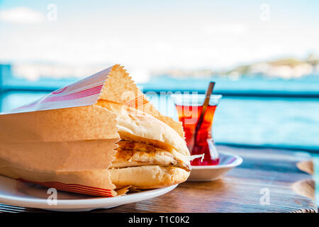 Tradizionale panino turco - 'Balik ekmek' e tè in un tulipano a forma di tazza di trazione. Messa a fuoco selettiva. Foto Stock