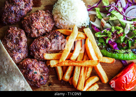 Tradizionale turca polpette - 'kofte'. Servito con patate fritte, riso e insalata di verdure. Foto Stock