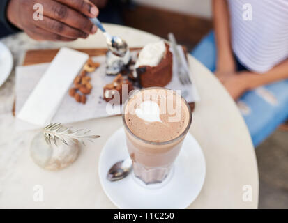 Due amici gustando un caffè e dessert di condivisione al cafè sul marciapiede Foto Stock