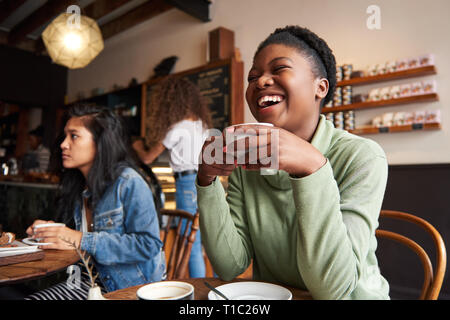Foto sincera di una giovane donna afroamericana che ride di un caffè con gli amici in un bar Foto Stock