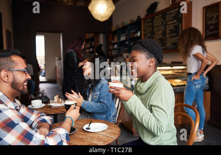 Sorridente giovani amici parlare insieme in un caffè in un bar Foto Stock