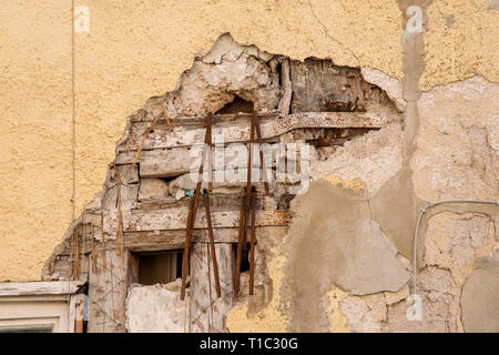 Foro nel muro di una casa in gesso con mattoni e travi di ferro Foto Stock