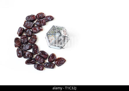 Il Ramadan, iftar tabella composizione. Data secchi Frutta disposte in luna e argento lanterna arabi isolati su sfondo bianco. Parte della decorazione. Patte di cibo Foto Stock