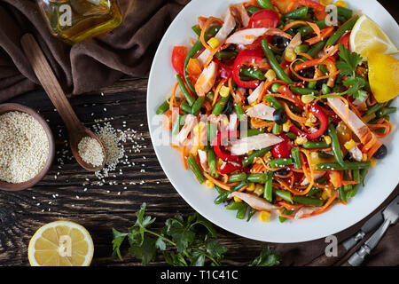 In stile messicano sani con insalata verde fagiolo, peperoni, olive nere, carota, mais e prosciutto tagliato in strisce su una piastra bianca su un tavolo rustico con il da Foto Stock