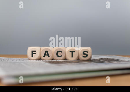 Dadi collocato su un quotidiano di formare la parola "i fatti". Foto Stock