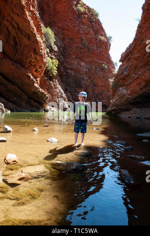 Un 6 anno vecchio ragazzo gioca sulle pietre miliari nelle acque basse di The Simpsons Gap, Territorio del Nord, l'Australia Foto Stock
