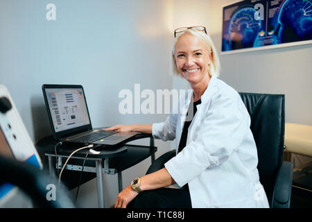 Ritratto femminile di lavoro medico in ospedale Office con computer sorridente Foto Stock
