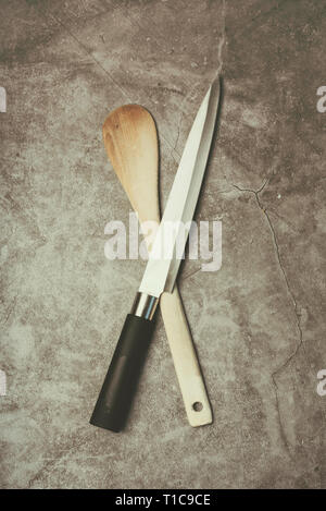 Coltello da cucina e il cucchiaio di legno contro sfondo Grunge Foto Stock