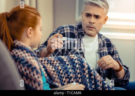 Cupa ansiosi uomo maturo tenendo un termometro Foto Stock