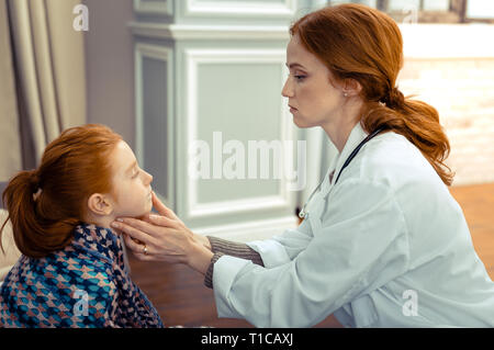 Professionista serio terapeuta controllare i suoi pazienti la salute Foto Stock