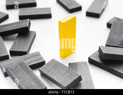 Uno giallo blocco di legno che si erge tra i caduti quelli neri Foto Stock