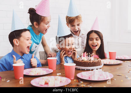 Ragazzo soffiando candele sulla torta di compleanno e festeggiare con gli amici Foto Stock