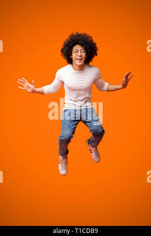 Allegro afro-americano guy ricci salti in aria Foto Stock