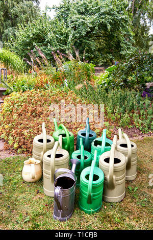 Molti vecchi innaffiatoi in un giardino. Foto Stock