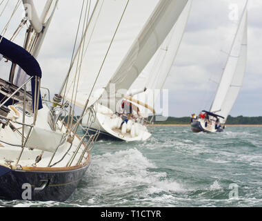 Tre belle barche Barche a vela con vele bianche racing vicini gli uni agli altri in una luminosa giornata di sole Foto Stock