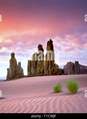 Dune di sabbia e Totem Pole formazione rocciosa a sunrise. Il Monument Valley, Arizona Foto Stock