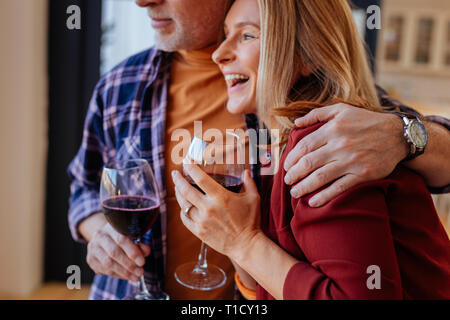 Barbuto marito indossando mano guarda abbraccia il suo ridendo moglie Foto Stock