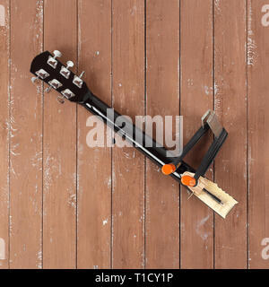 La riparazione di una chitarra e il servizio di assistenza - il serraggio di una chitarra collo alto vista sullo sfondo di legno Foto Stock