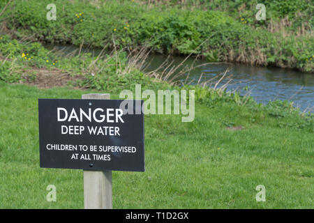 Segno accanto a un fiume avvertenza Pericolo acqua profonda, i bambini devono essere sorvegliati in tutti i tempi, REGNO UNITO Foto Stock
