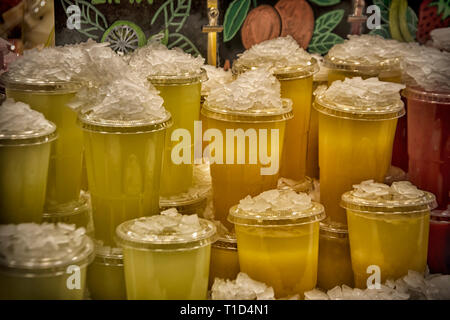 Bicchieri in plastica colorata con succhi di frutta freschi al mercato Foto Stock