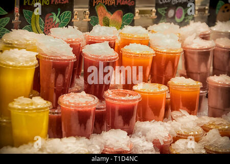 Bicchieri in plastica colorata con succhi di frutta freschi al mercato Foto Stock