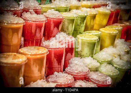 Bicchieri in plastica colorata con succhi di frutta freschi al mercato Foto Stock