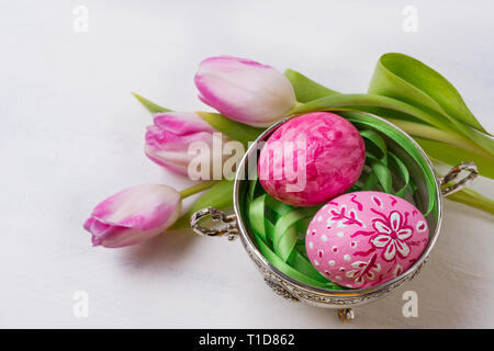 Centrotavola da tavolo di Pasqua con uova rosa, verde, giallo e tulipani  nel vaso bianco vicino muro di mattoni dipinti Foto stock - Alamy