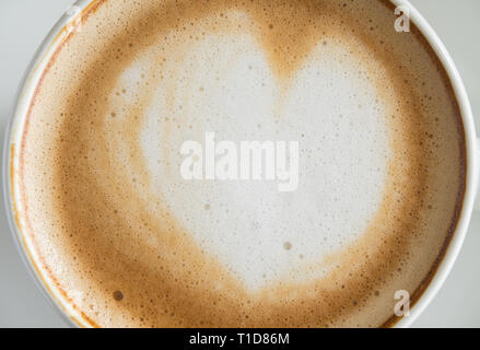 Flatlay forma di cuore Latte Latte Art in bianco tazza di caffè vicino sul legno nero tabella. Forma di cuore Latte Latte Art bevanda calda per il caffè lo Foto Stock