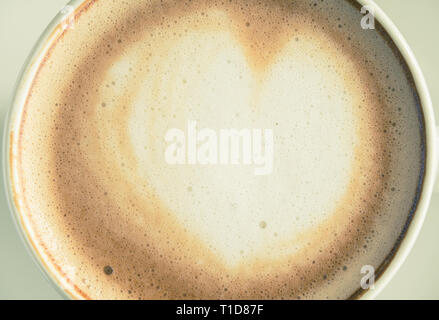 Vintage Flatlay forma di cuore Latte Latte Art in bianco tazza di caffè vicino sul legno nero tabella. Forma di cuore Latte Latte Art bevanda calda per c Foto Stock