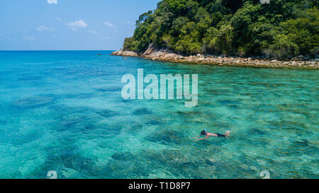 L uomo lo snorkeling da soli in un mare tropicale sulla barriera corallina con chiaro blu acqua cristallina. Perhentian Island, Malaysia Foto Stock