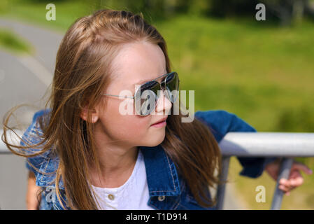 Ragazza con occhiali da sole che pongono al di fuori in parco nella luce  solare con pubblicità spazio di copia Foto stock - Alamy