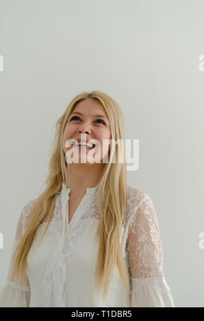 Ritratto di giovane meravigliosa donna con capelli lunghi biondi e gli occhi verdi è sorridente su sfondo bianco. Bel ritratto di donna, grande vere emozioni Foto Stock