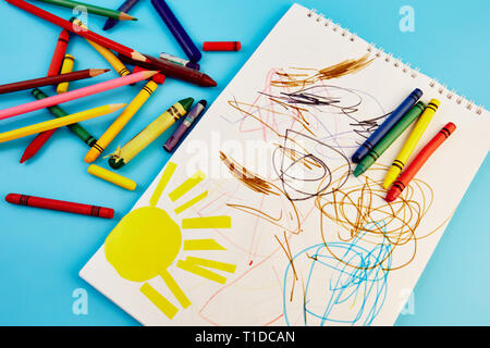 Matite colorate e figli di disegni su uno sfondo blu Foto Stock