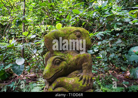 Una statua di pietra del monitor di Komodo, coperto di muschi e licheni in un verde tropicale foresta vicino al fiume. Lucertola gigante nella Sacra Foresta delle Scimmie, Ub Foto Stock