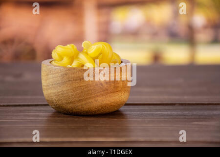 Sacco di tutta la pasta cavatappi con ciotola di legno con carrello in background Foto Stock