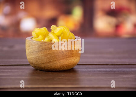 Sacco di tutta la pasta cavatappi con ciotola di legno in un legno rustico cucina Foto Stock