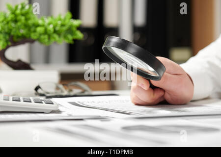 Imprenditore lavora in ufficio e il calcolo delle finanze. Utilizzando la lente di ingrandimento. Azienda di contabilità finanziaria concetto. Foto Stock