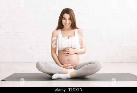 Attiva donna incinta seduta sul pavimento dopo facendo sport Foto Stock