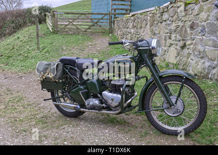 Trionfo classico TRW 500cc motociclo militare parcheggiata da una pietra costruito il muro e cancello di legno in una fattoria nel Galles del Nord Foto Stock