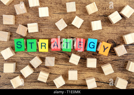 Il concetto: la strategia di plastica colorata lettere illustra la strategia di parola con il giocattolo di legno cubi Foto Stock