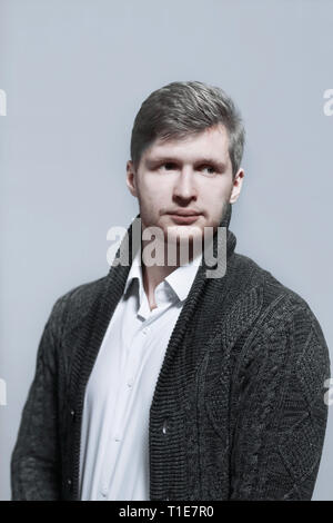 Elegante giovane uomo in una maglia cardigan.isolato su sfondo grigio Foto Stock